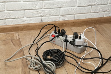 Photo of Extension power board overloaded with plugs on wooden floor