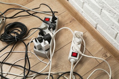 Photo of Extension power boards overloaded with plugs on wooden floor