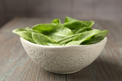 Photo of Fresh green sorrel leaves in bowl on wooden table, closeup