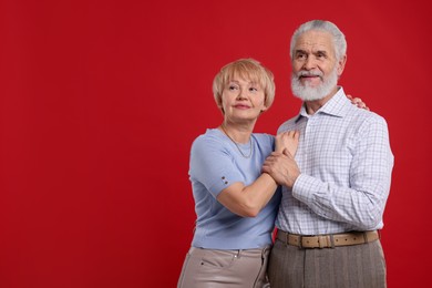 Photo of Lovely senior couple holding hands on red background. Space for text