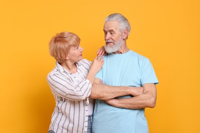 Photo of Lovely senior couple looking at each other on orange background