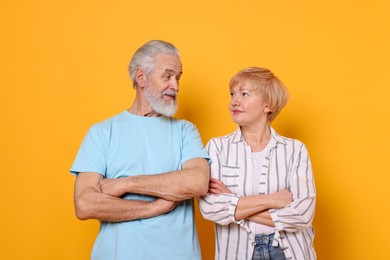 Photo of Lovely senior couple looking at each other on orange background