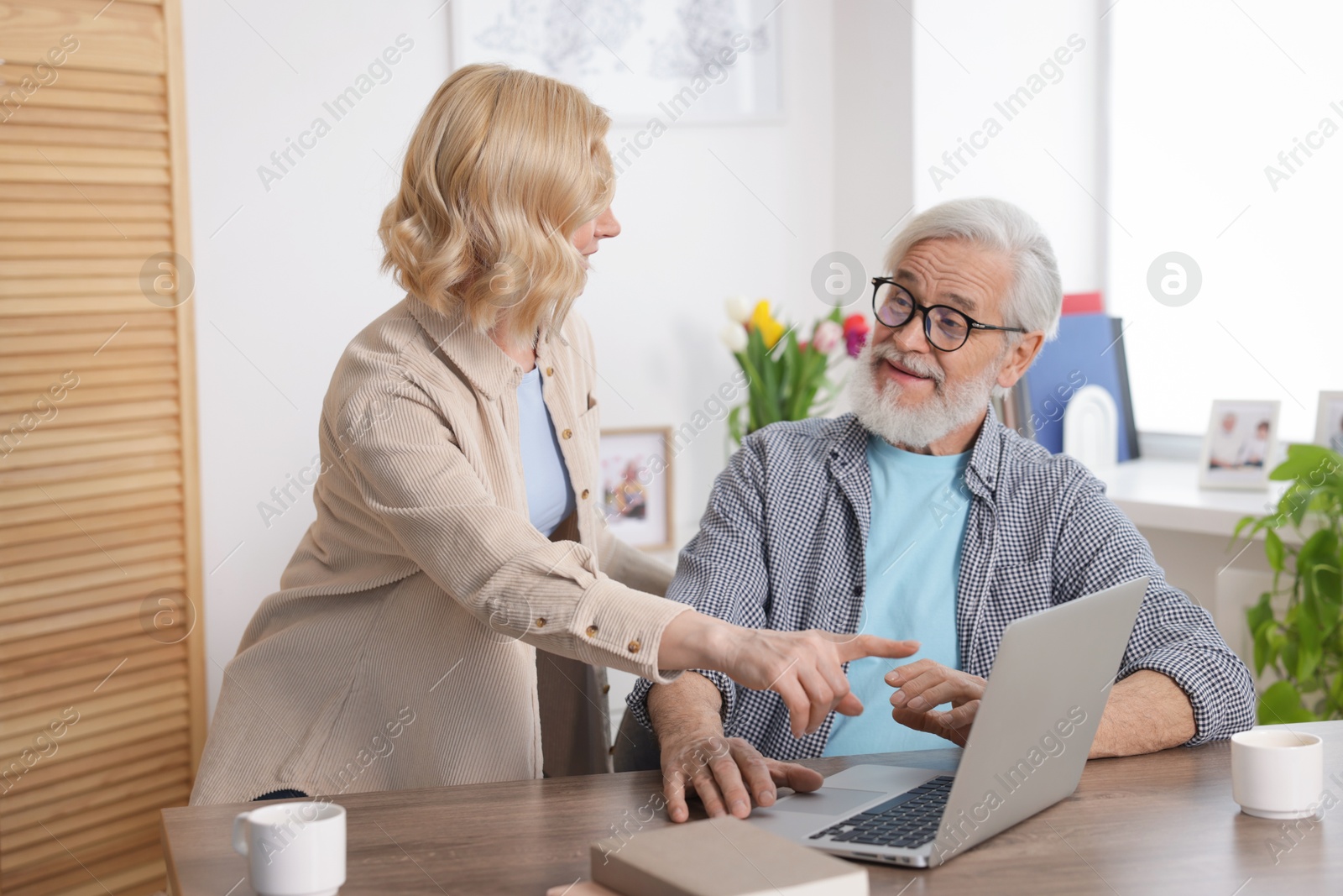 Photo of Senior man and mature woman with laptop at home. Happy couple