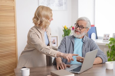 Photo of Senior man and mature woman with laptop at home. Happy couple