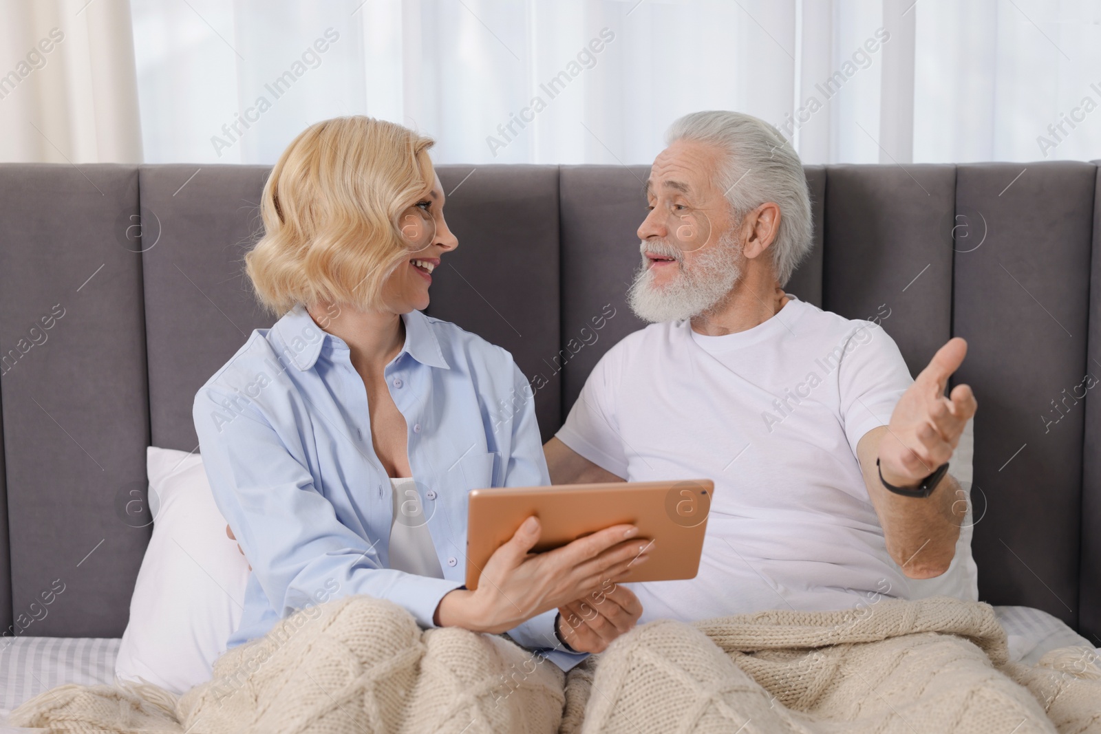 Photo of Senior man and mature woman with tablet spending time together at home. Happy couple