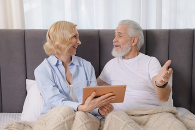 Photo of Senior man and mature woman with tablet spending time together at home. Happy couple