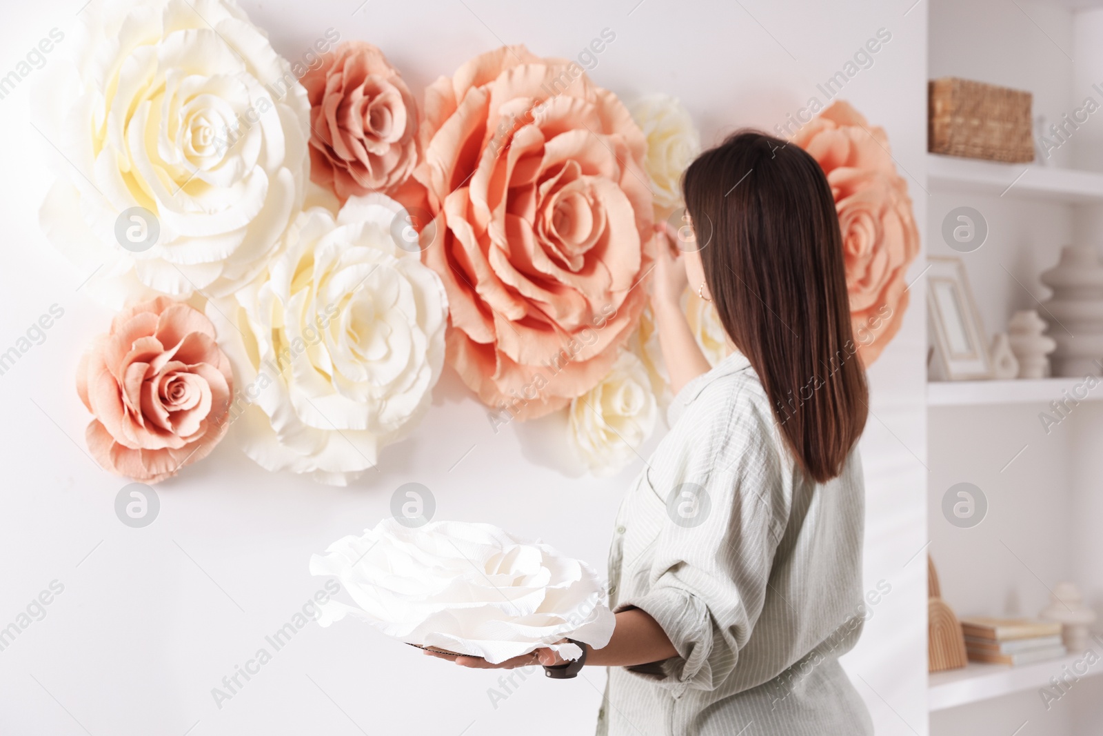 Photo of Woman decorating wall with beautiful paper flowers at home