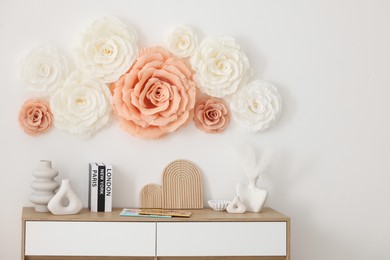 Photo of Beautiful decorative paper flowers on wall in room