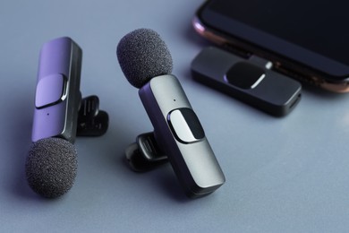 Photo of Lavalier microphones and smartphone on light grey background, closeup