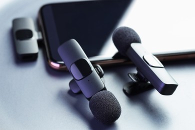 Photo of Lavalier microphones and smartphone on light grey background, closeup