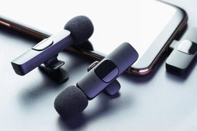 Photo of Lavalier microphones and smartphone on light grey background, closeup