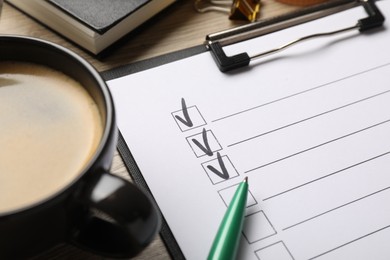 Photo of Checklist with marked checkboxes, stationery and coffee on table, closeup