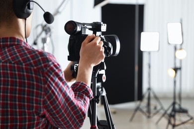 Photo of Man with professional video camera in studio, closeup. Space for text