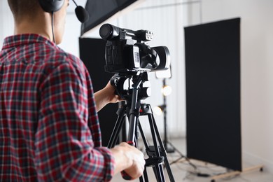 Photo of Man with professional video camera in studio, closeup. Space for text