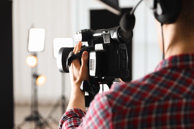 Photo of Man with professional video camera in studio, closeup. Space for text