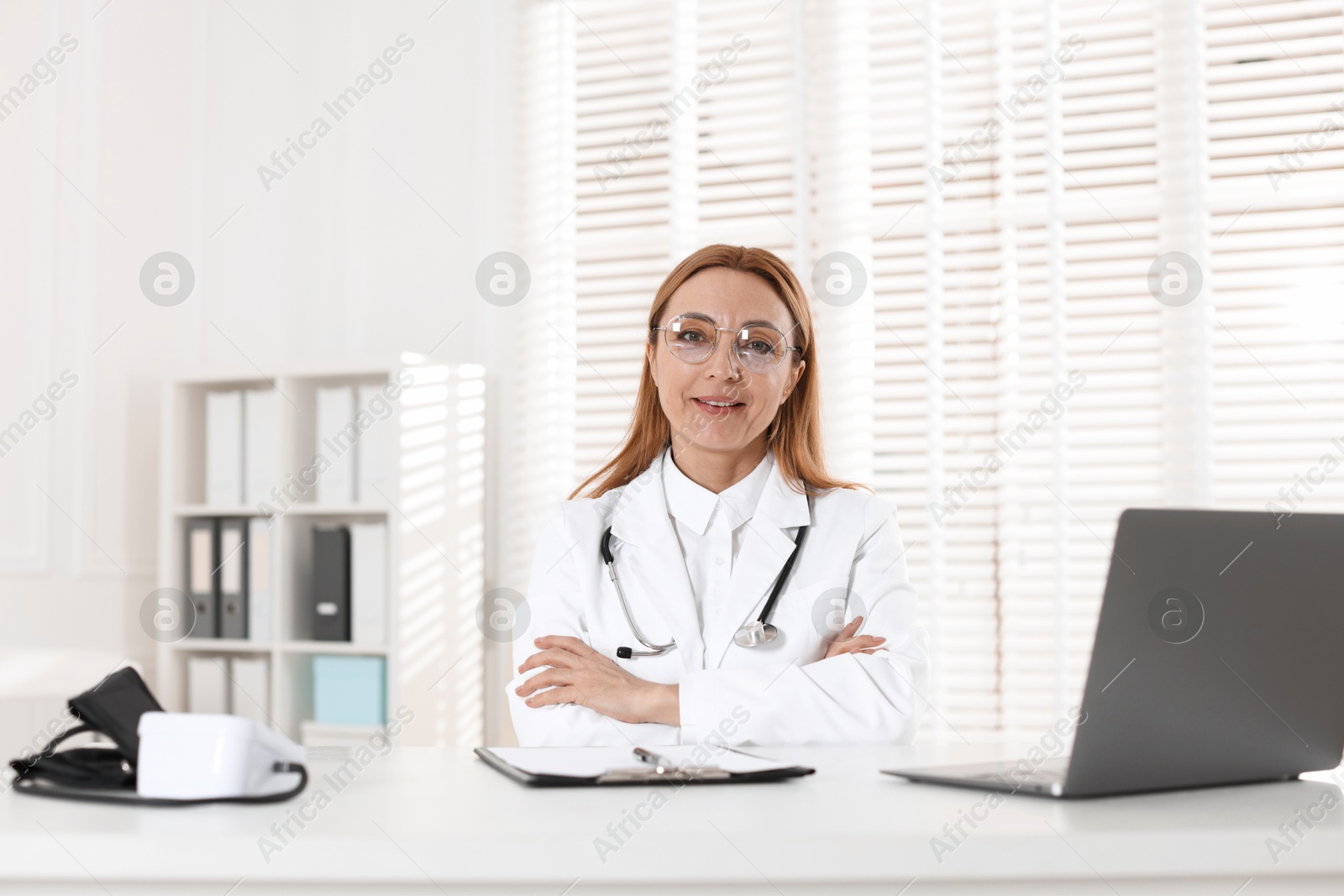 Photo of Cardiologist with stethoscope at white table in clinic