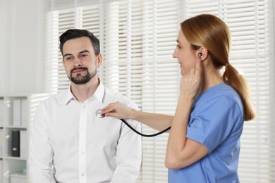 Photo of Cardiologist with stethoscope listening patient's heartbeat in hospital