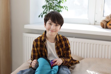 Photo of Boy packing backpack for school on bed at home