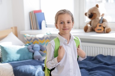 Photo of Portrait of little girl with backpack at home