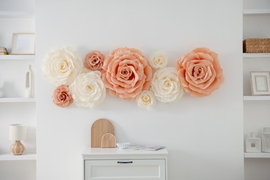 Photo of Beautiful decorative paper flowers on wall in room