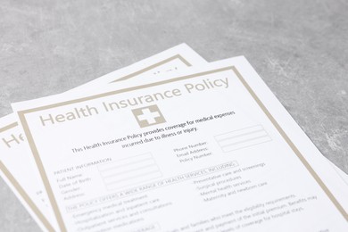 Photo of Health insurance policy forms on grey table, closeup