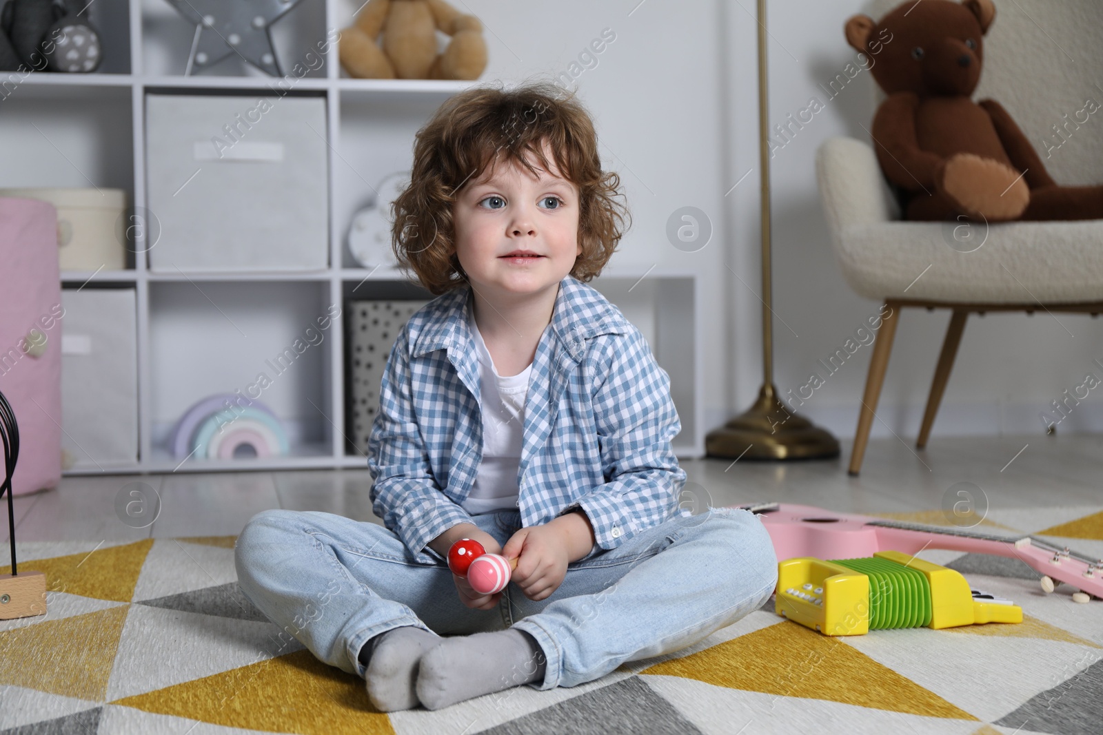 Cute little boy playing toy maracas on floor at home Photo of Cute little boy playing toy maracas on floor at home
