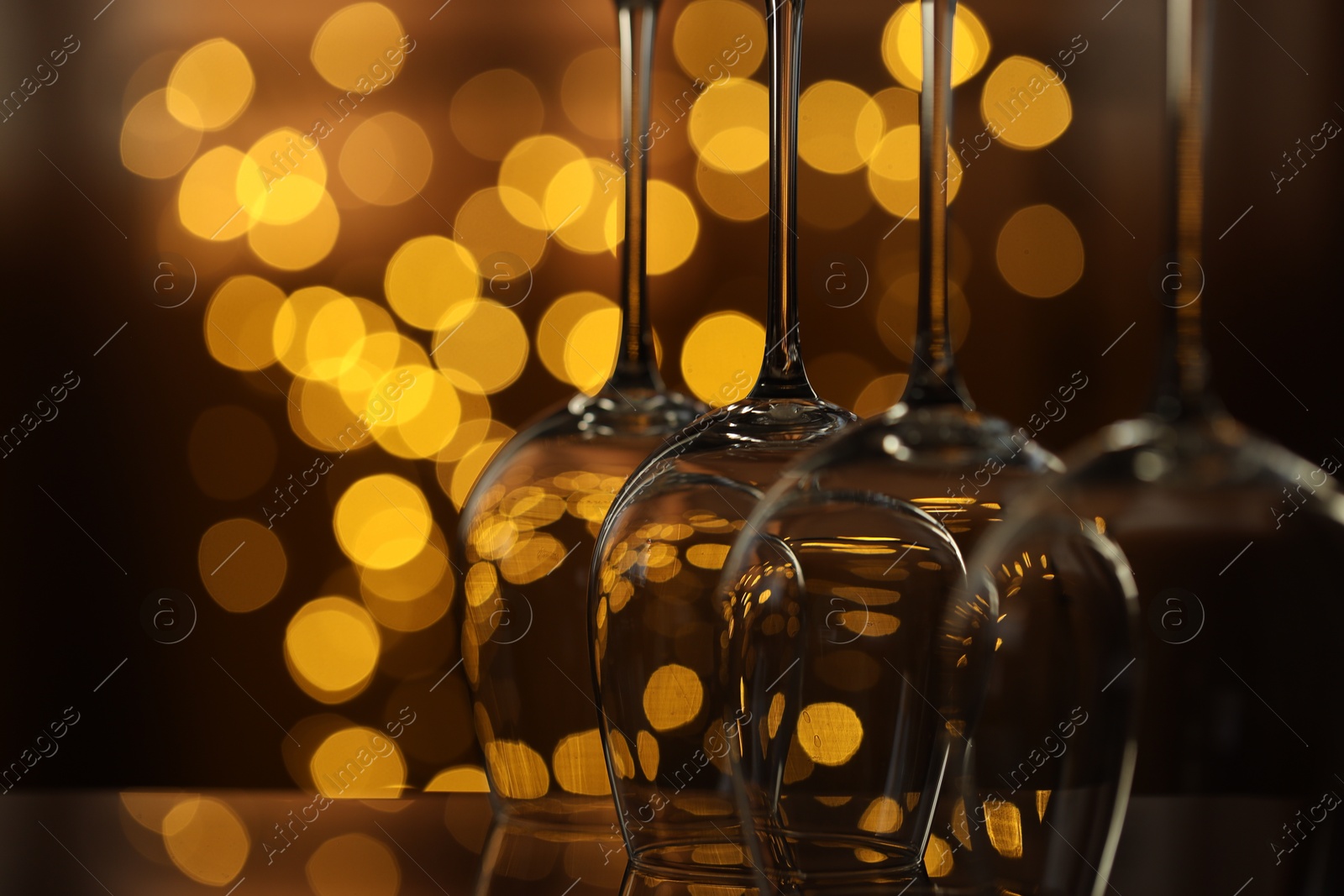 Many clean glasses on glass mirror surface against blurred lights, closeup. Bokeh effect Photo of Many clean glasses on glass mirror surface against blurred lights, closeup. Bokeh effect