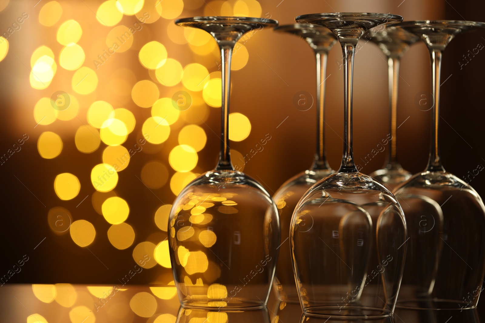Many clean glasses on glass mirror surface against blurred lights. Bokeh effect Photo of Many clean glasses on glass mirror surface against blurred lights. Bokeh effect
