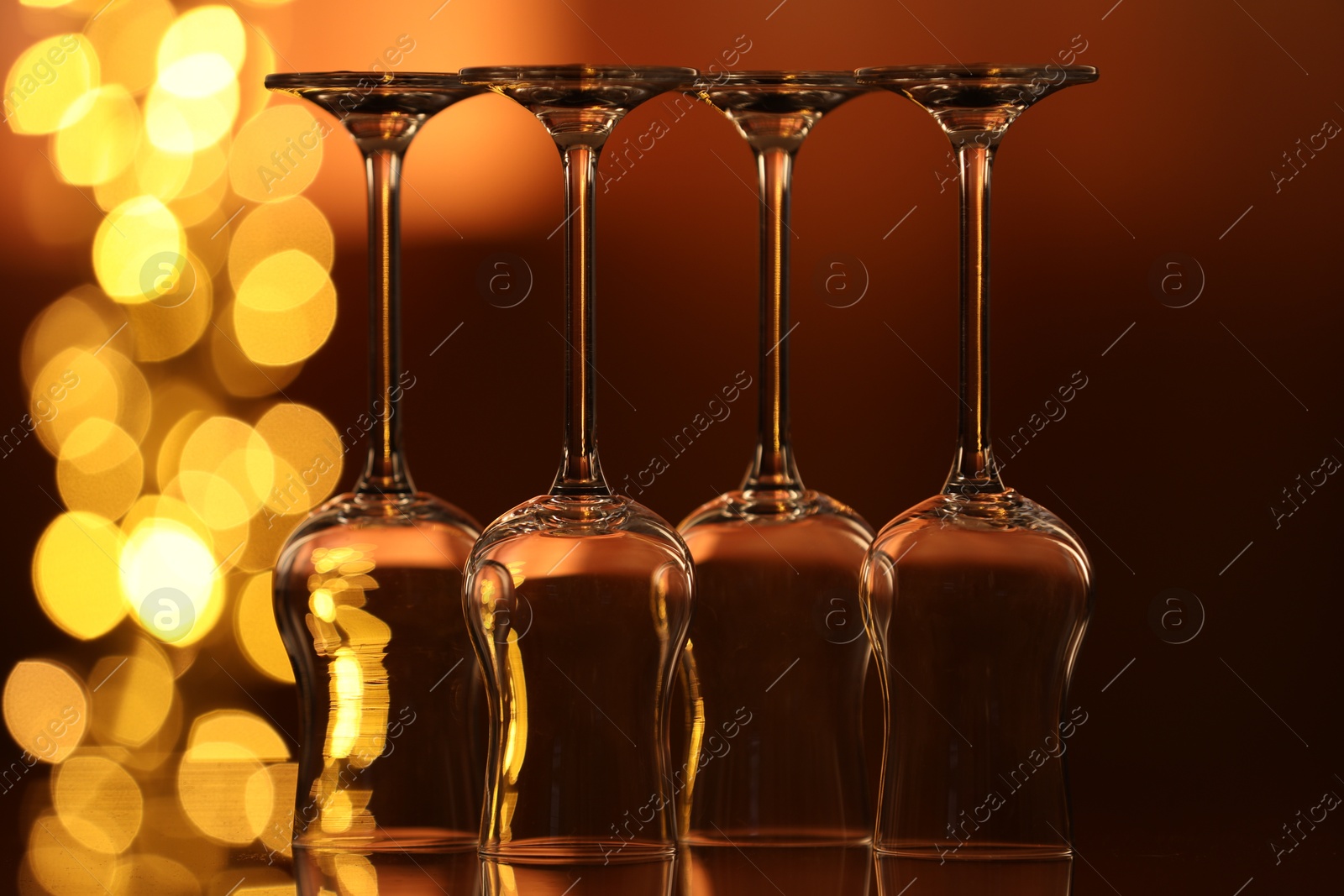 Many clean glasses on glass mirror surface against blurred lights. Bokeh effect Photo of Many clean glasses on glass mirror surface against blurred lights. Bokeh effect