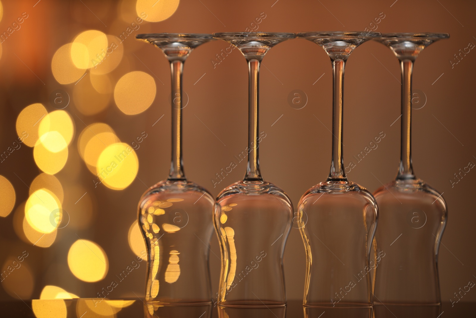Many clean glasses on glass mirror surface against blurred lights. Bokeh effect Photo of Many clean glasses on glass mirror surface against blurred lights. Bokeh effect