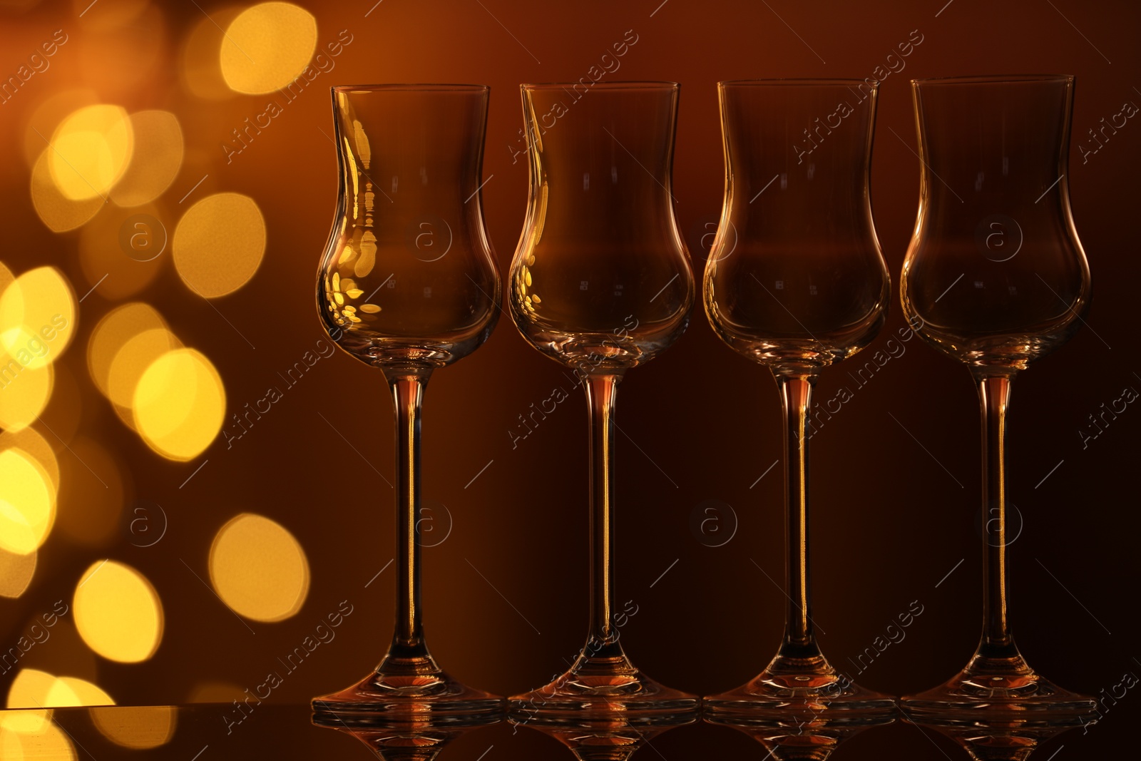 Many clean glasses on glass mirror surface against blurred lights. Bokeh effect Photo of Many clean glasses on glass mirror surface against blurred lights. Bokeh effect