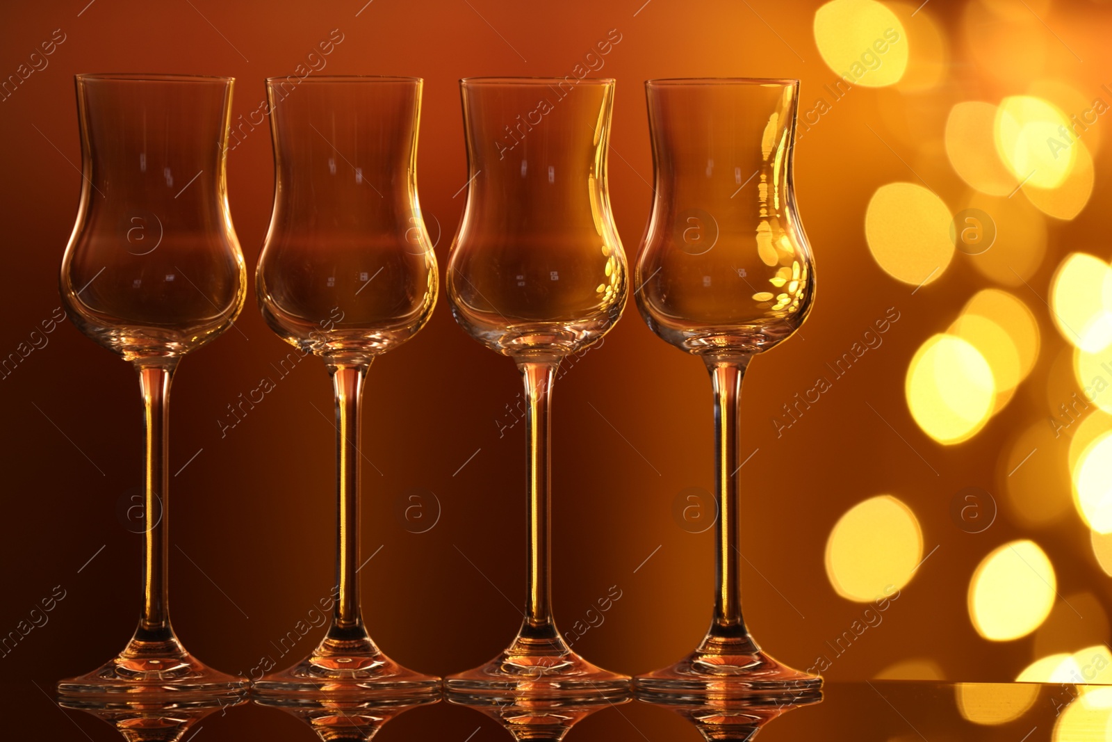 Many clean glasses on glass mirror surface against blurred lights. Bokeh effect Photo of Many clean glasses on glass mirror surface against blurred lights. Bokeh effect