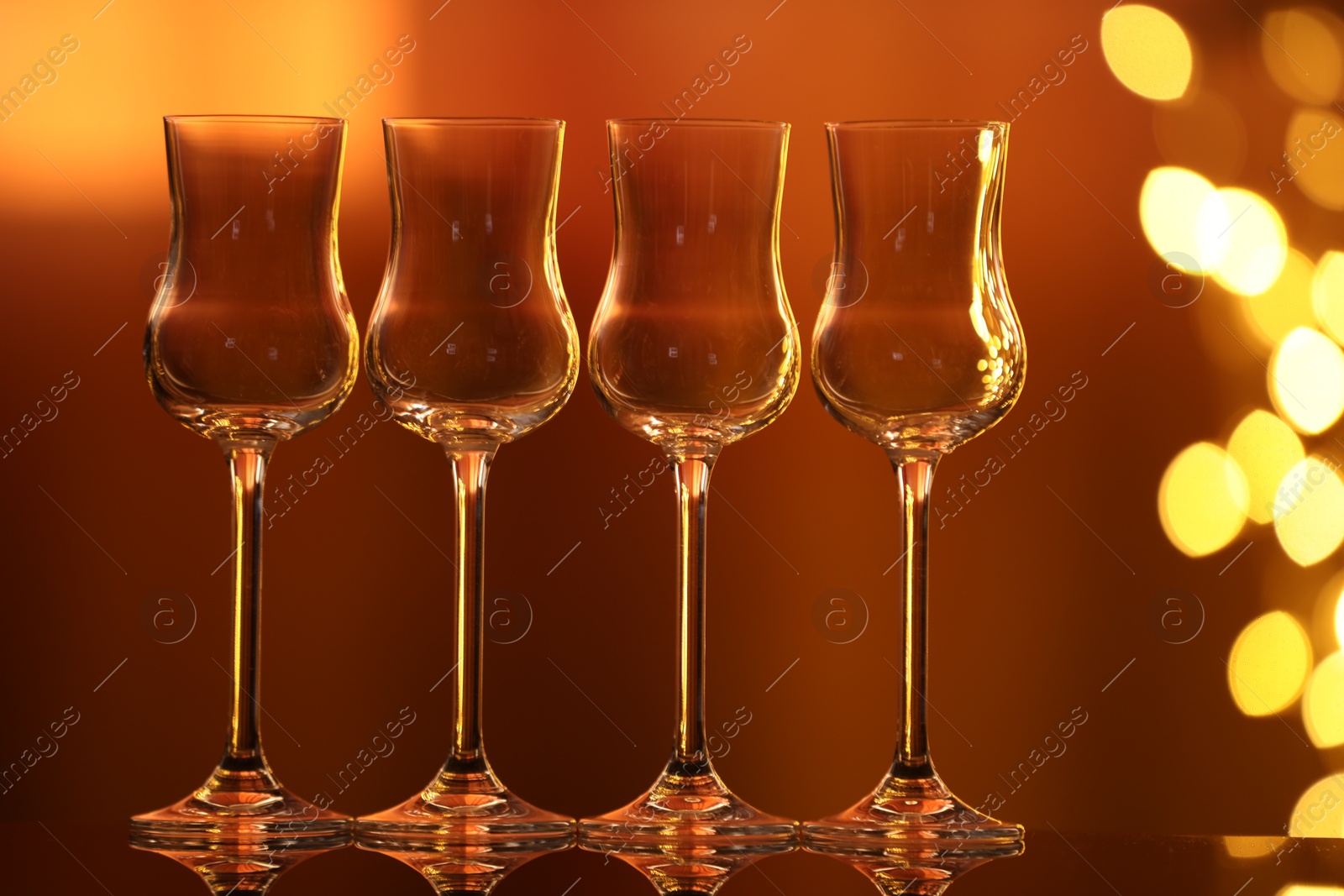 Many clean glasses on glass mirror surface against blurred lights. Bokeh effect Photo of Many clean glasses on glass mirror surface against blurred lights. Bokeh effect