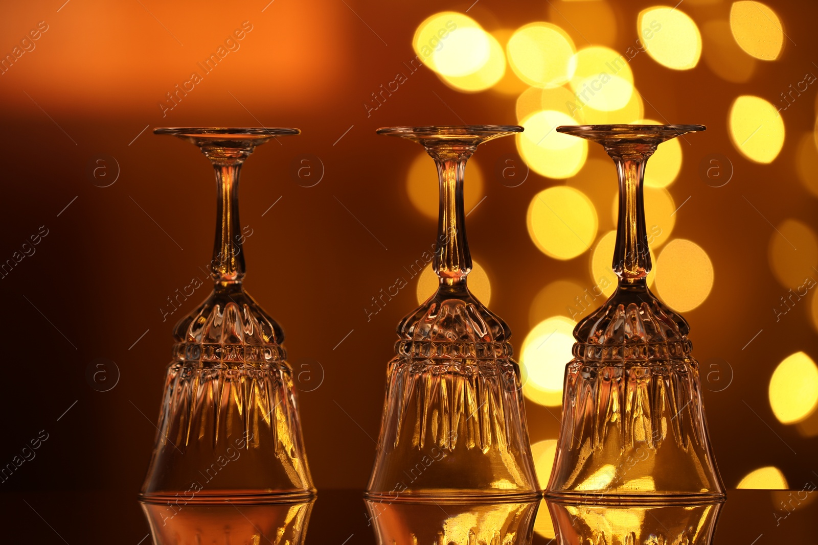 Many clean glasses on glass mirror surface against blurred lights. Bokeh effect Photo of Many clean glasses on glass mirror surface against blurred lights. Bokeh effect