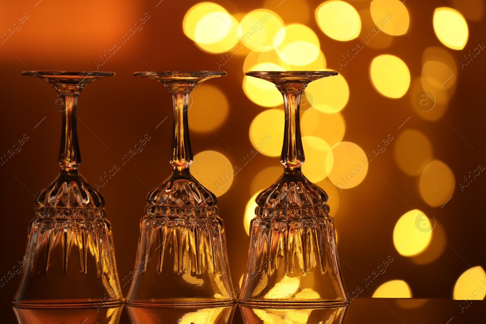 Many clean glasses on glass mirror surface against blurred lights. Bokeh effect Photo of Many clean glasses on glass mirror surface against blurred lights. Bokeh effect
