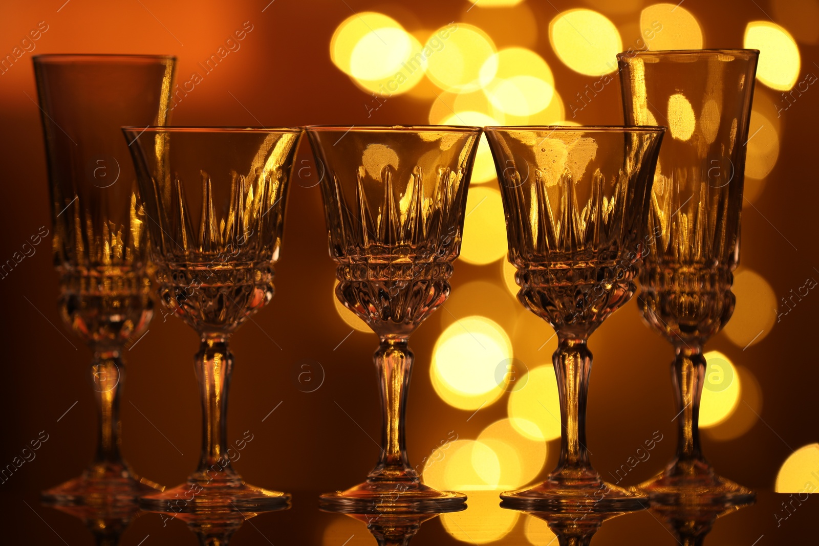 Many clean glasses on glass mirror surface against blurred lights. Bokeh effect Photo of Many clean glasses on glass mirror surface against blurred lights. Bokeh effect