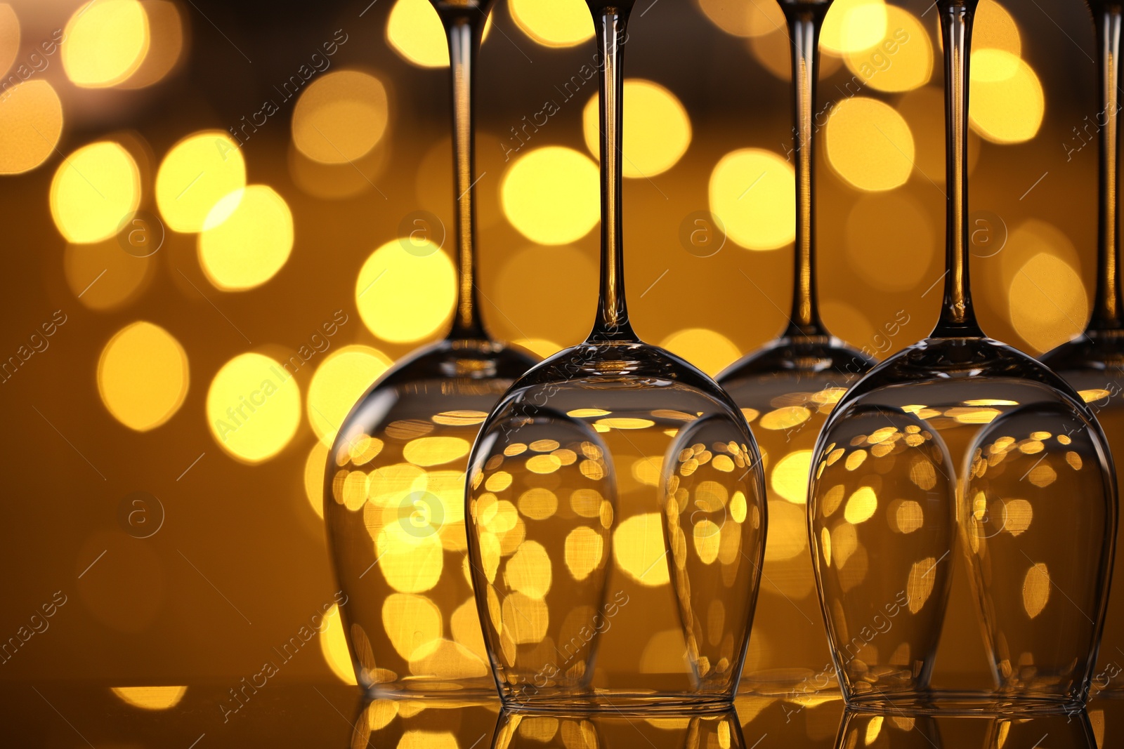 Many clean glasses on glass mirror surface against blurred lights, closeup. Bokeh effect Photo of Many clean glasses on glass mirror surface against blurred lights, closeup. Bokeh effect