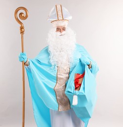 Photo of Saint Nicholas with bag of Christmas gifts and crozier on gray background