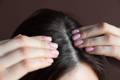 Photo of Woman with healthy hair roots on brown background, closeup