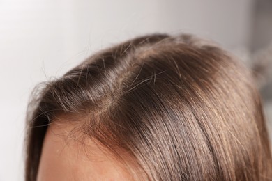 Photo of Woman with healthy hair roots on blurred background, closeup