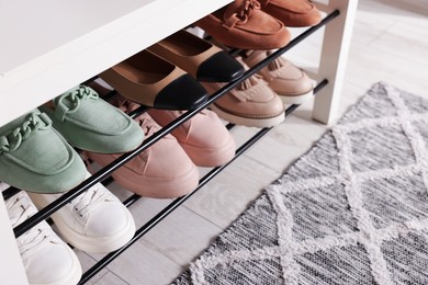 Photo of Stand with different stylish shoes indoors, closeup. Space for text