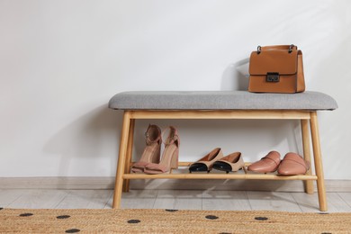 Photo of Stand with different stylish shoes and bag indoors. Space for text