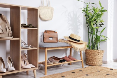 Photo of Stands with different stylish shoes, straw hats, bag and houseplant indoors