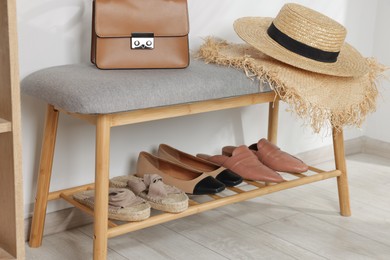 Photo of Stand with different stylish shoes, straw hats and bag indoors