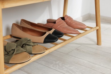 Photo of Stand with different stylish shoes indoors, closeup