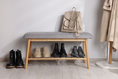 Photo of Stand with different stylish shoes and bag indoors
