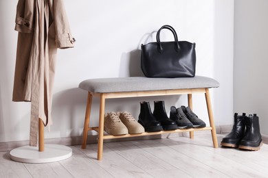 Photo of Stand with different stylish shoes and bag indoors