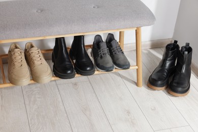 Photo of Stand with different stylish shoes indoors. Space for text