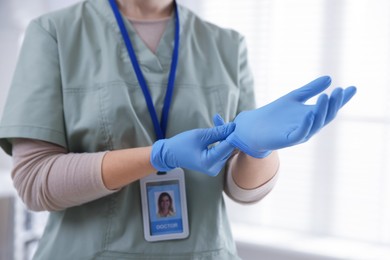 Photo of Medical worker putting on gloves in hospital, closeup