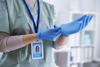 Photo of Medical worker putting on gloves in hospital, closeup